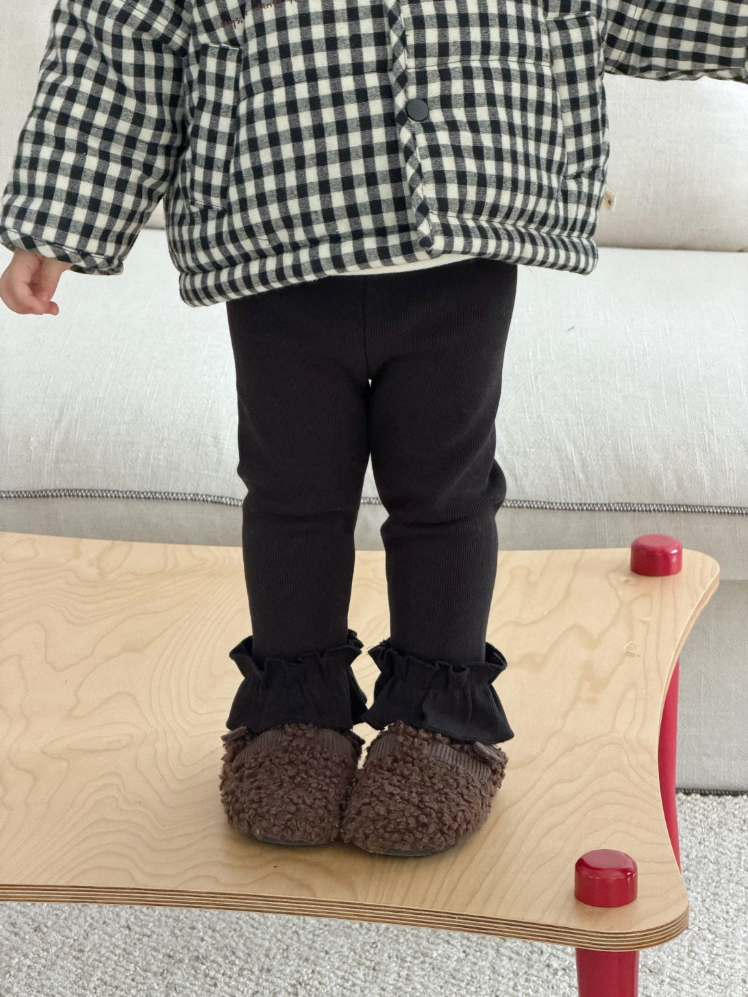 チェック柄中綿ジャケットの裾、黒パンツとフリル裾の重ね見え