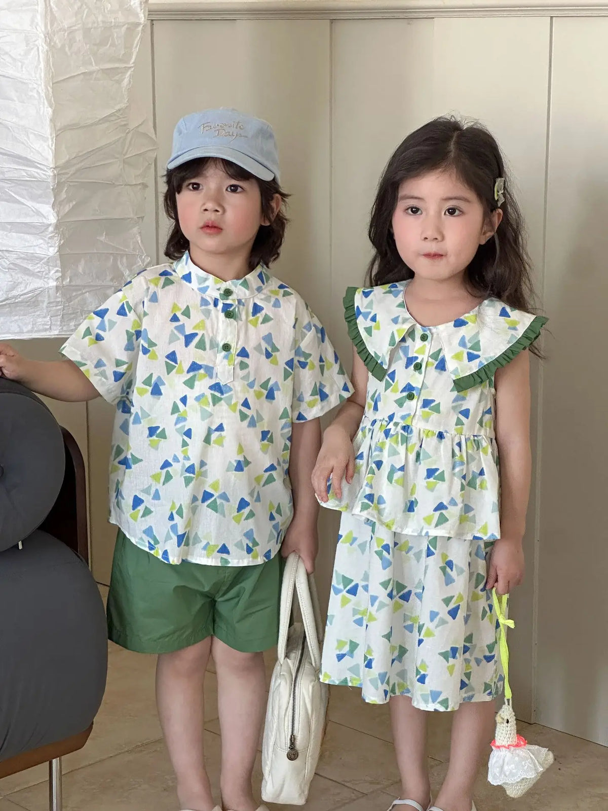 幾何学柄プリントの子どもワンピースセット、フリル襟とペプラム、グリーンのショートパンツ付き