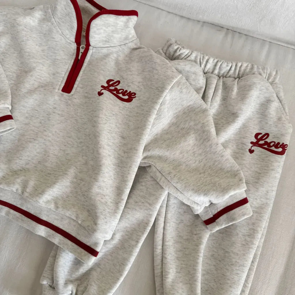 グレー系スウェット上下セットのアップ、ハーフジップと刺繍ロゴ、赤縁取り