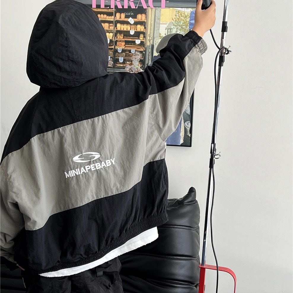 キッズ用ウィンドブレーカー、フード付き黒×グレーのカラーブロック、胸のロゴ
