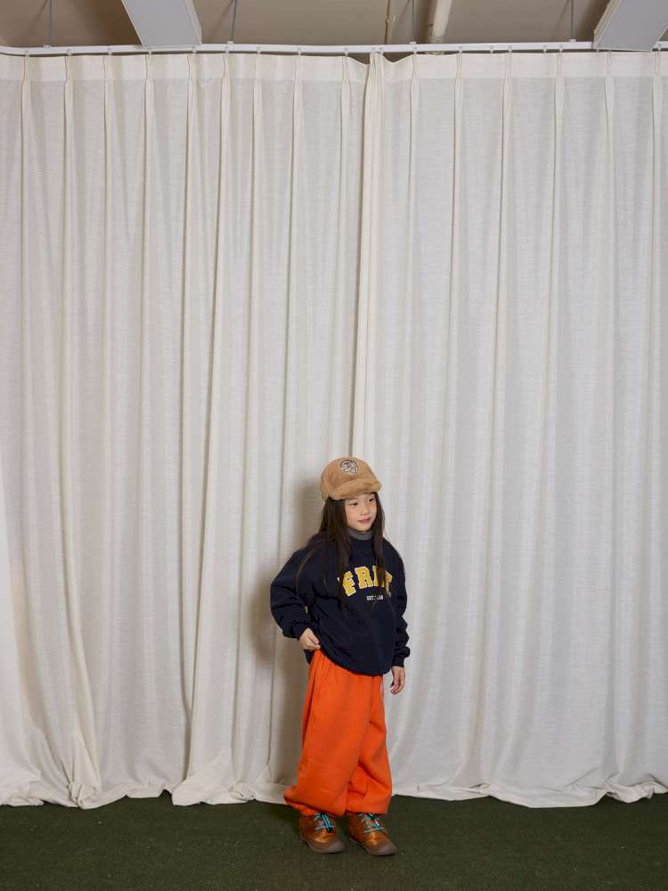 刺繍入りプリント裏起毛セットアップ:黒のスウェット上着、オレンジのスウェットパンツ
