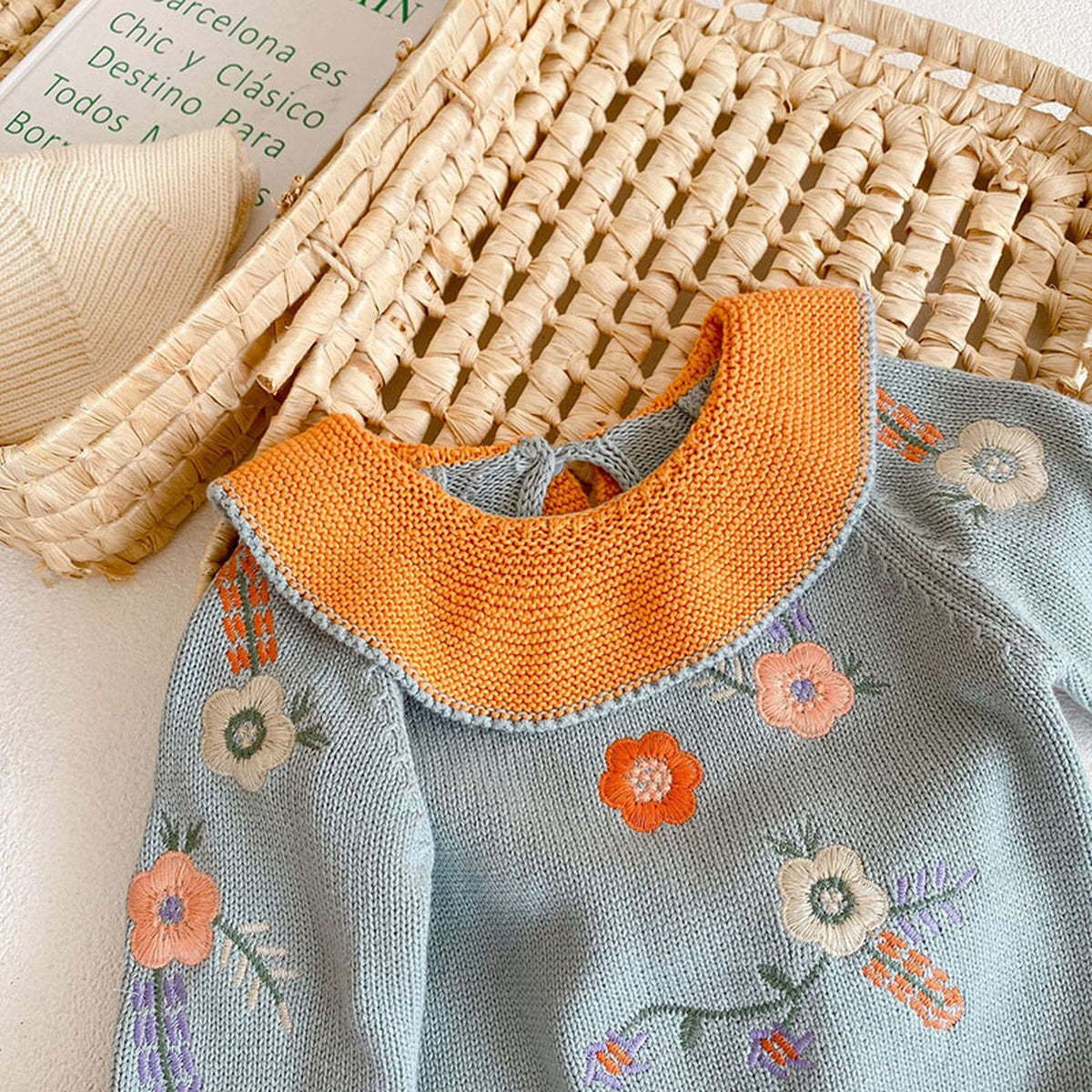 ベビー用ニットセーター前身ごろアップ、花刺繍とオレンジ配色襟