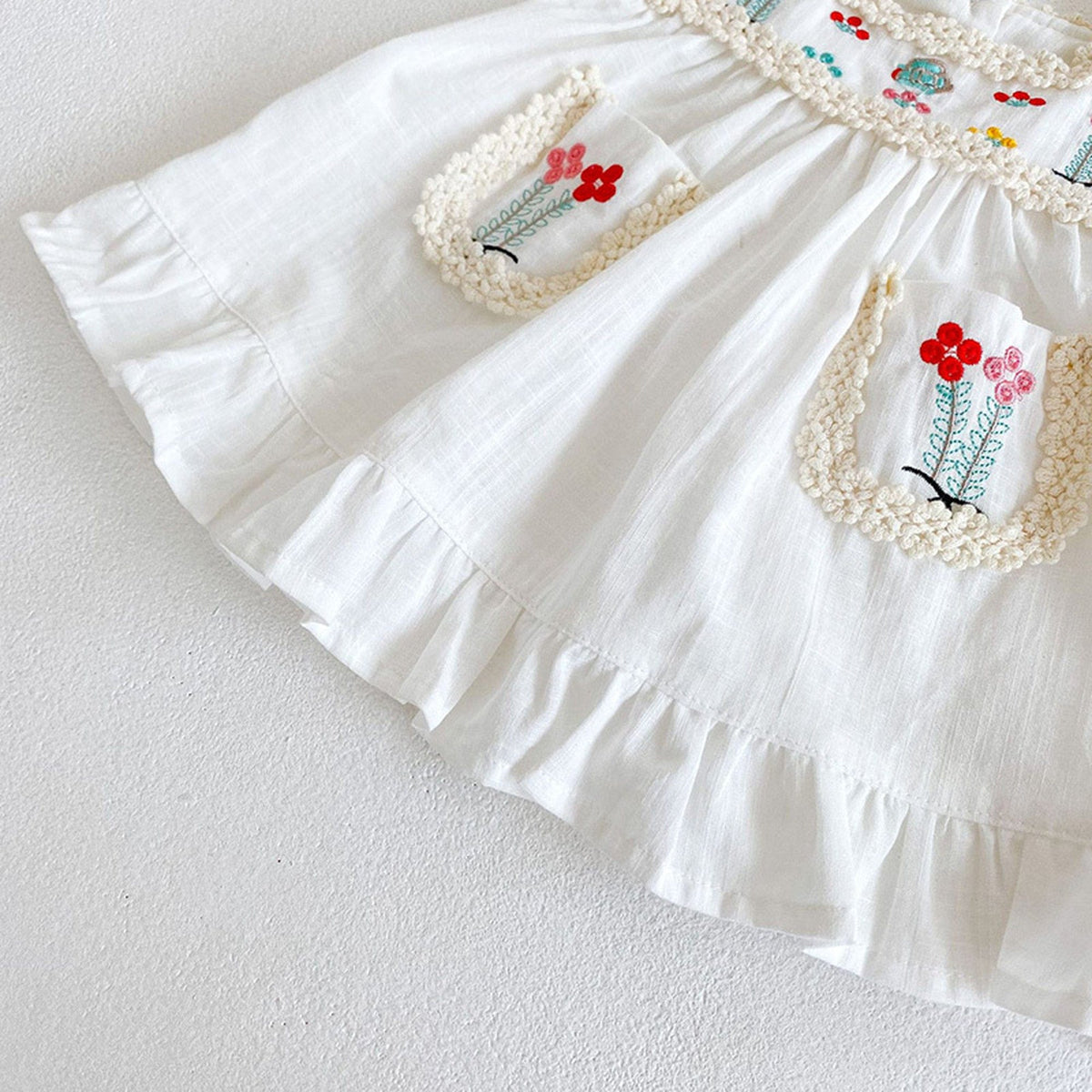 白いAラインノースリーブワンピース、花刺繍のアップリケと段フリル