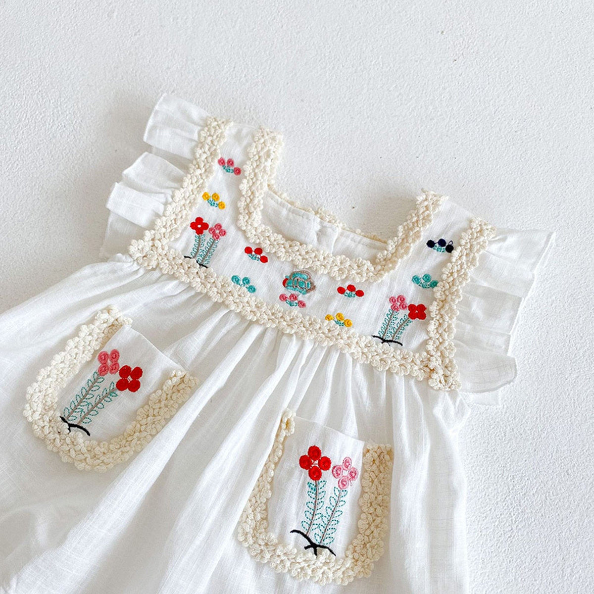 白いノースリーブAラインワンピース、花柄刺繍パネルとレース装飾