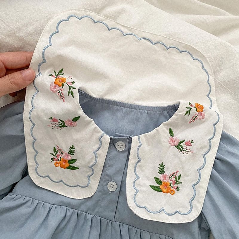 白いフリル襟付きライトブルーのロンパース、花刺繍と前ボタンのアップ