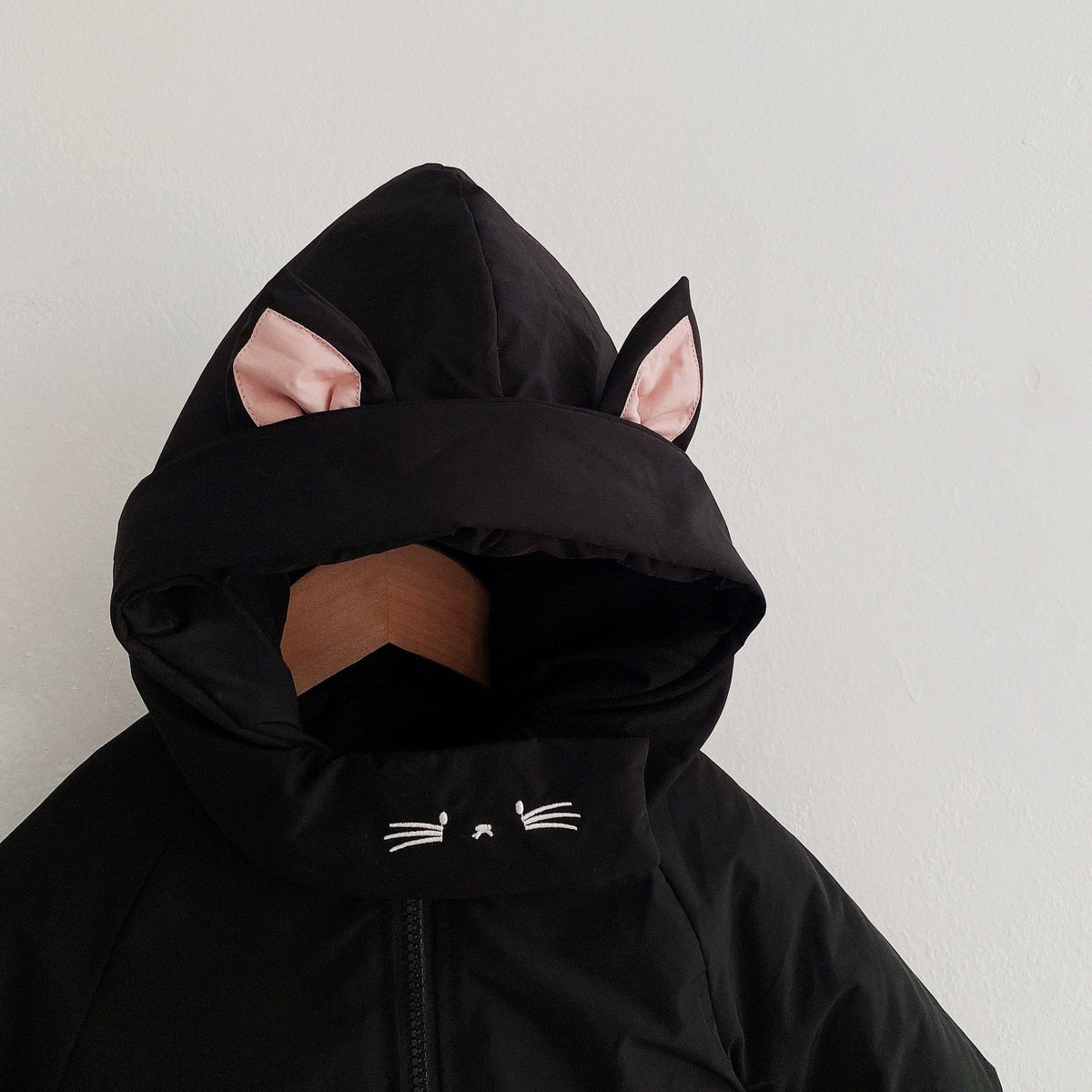黒の耳付きフードジャンプスーツ、フード内に猫耳デザインとフロント刺繍