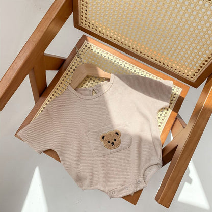ベージュのワッフル半袖ロンパース、前ポケットにクマ刺繍のアップ