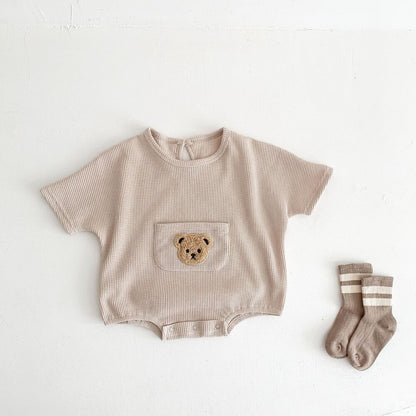 ベージュのワッフル半袖ロンパース、前ポケットにクマ刺繍とスナップボタン
