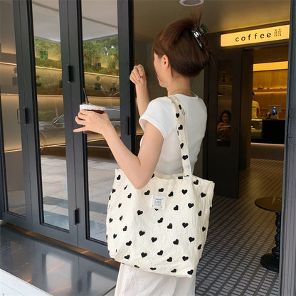 ハート柄キャンバストートを肩掛けした背面スタイル