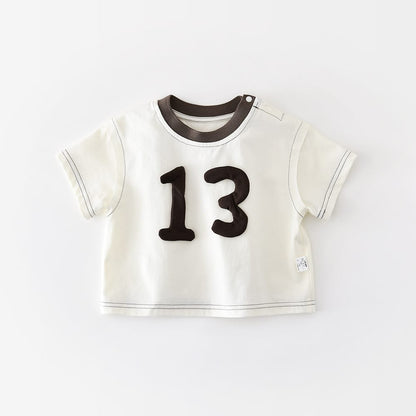 白い半袖Tシャツ。前面に立体パッチの数字13、ブラウンの丸首リブ付き