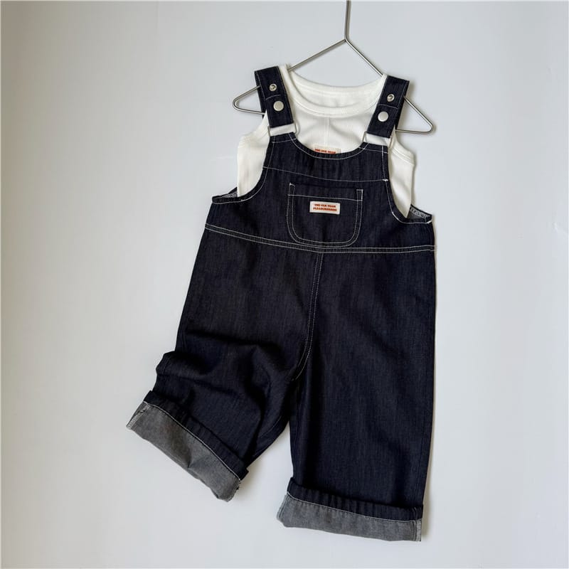 白Tシャツの上に着用したダークブルーデニムサロペット、肩ストラップ付き