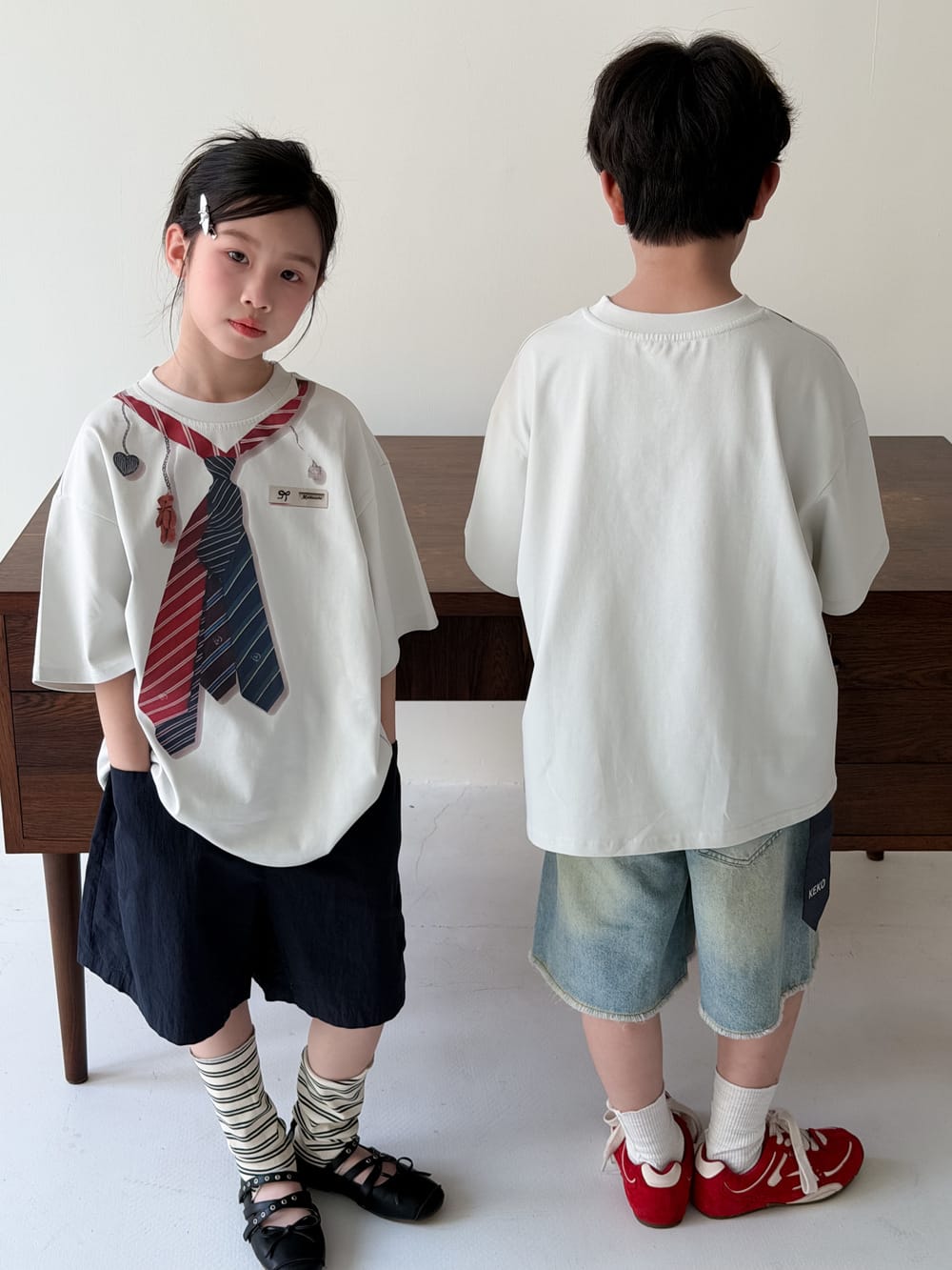 白の半袖Tシャツ、ネクタイ風プリント、背面は無地の丸首シルエット