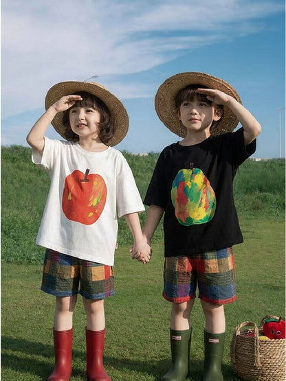草原で着用された白Tシャツと黒Tシャツ。フルーツ柄プリント付き。