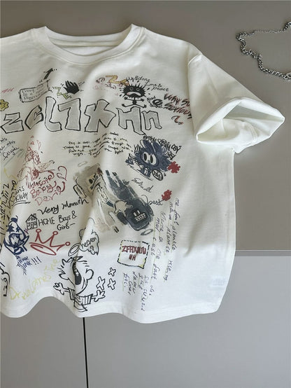 クリーム色の半袖クルーネックTシャツ、文字とキャラクターの落書きプリント