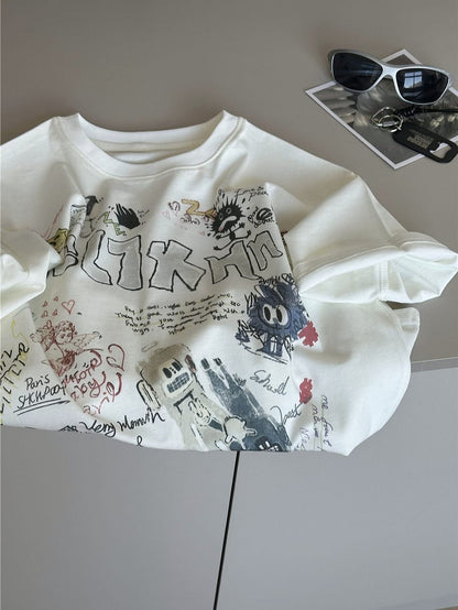 クリーム色半袖Tシャツ、落書き風の文字やキャラが散りばめられたプリント