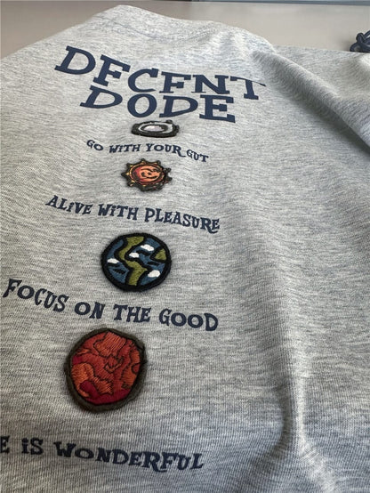 杢グレー半袖Tシャツ、背面の英字ロゴと刺繍風パッチ付きプリント