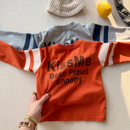 オレンジ色の長袖Tシャツ、ネイビー×白の袖口ラインと「Kiss Me」文字