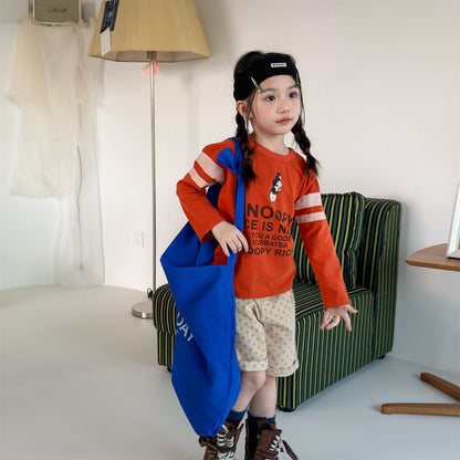 オレンジ色の長袖Tシャツ、スヌーピー風グラフィックとロゴプリント付き