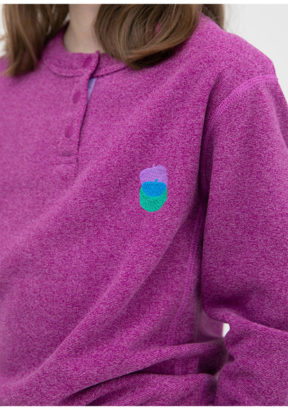 紫のキッズフリーストップスのアップ、胸の刺繍モチーフとボタンなしの前身頃