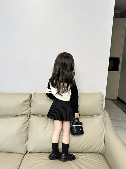 キッズ用プリーツミニスカートの後ろ姿、黒の長袖ニットポロとAライン