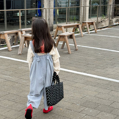 淡いブルーのデニムサロペットパンツ、背面の肩ひもと後ろ姿が見える