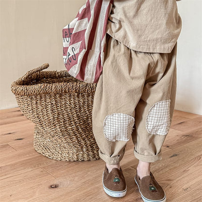 ベージュのゆったりキッズパンツ、ひざのチェックパッチ付き