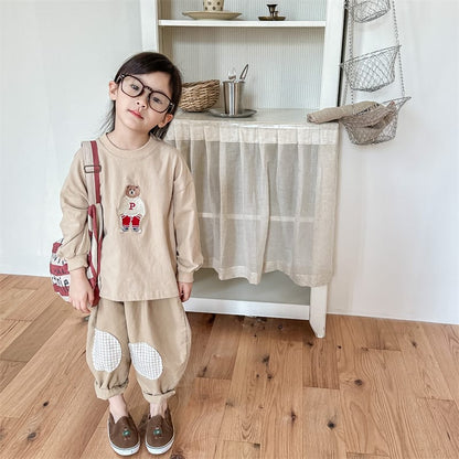 キッズ用膝パッチ付きルーズパンツ。ベージュ系、チェック柄の丸い膝当て。