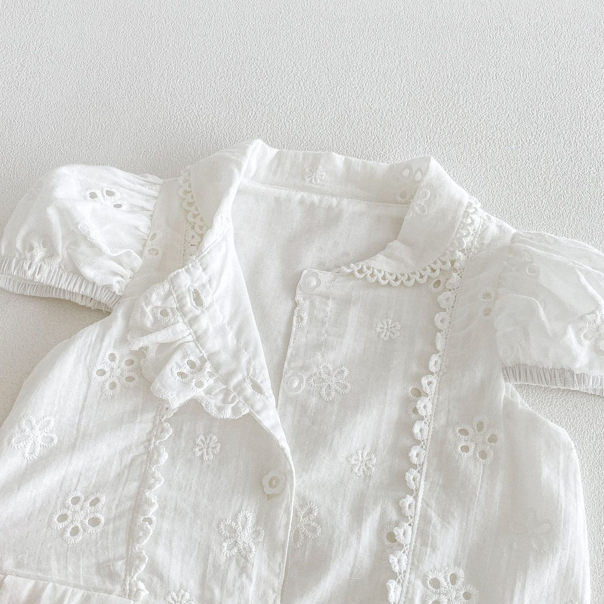 キッズ用ホワイト半袖ワンピース、前身頃の刺繍レースとボタンディテール