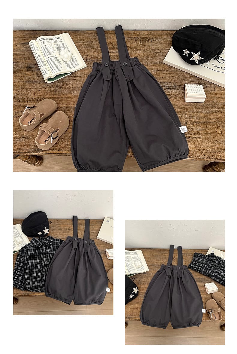 チャコールグレーのサロペットパンツ、前のタック風デザインと広がるバルーンシルエット