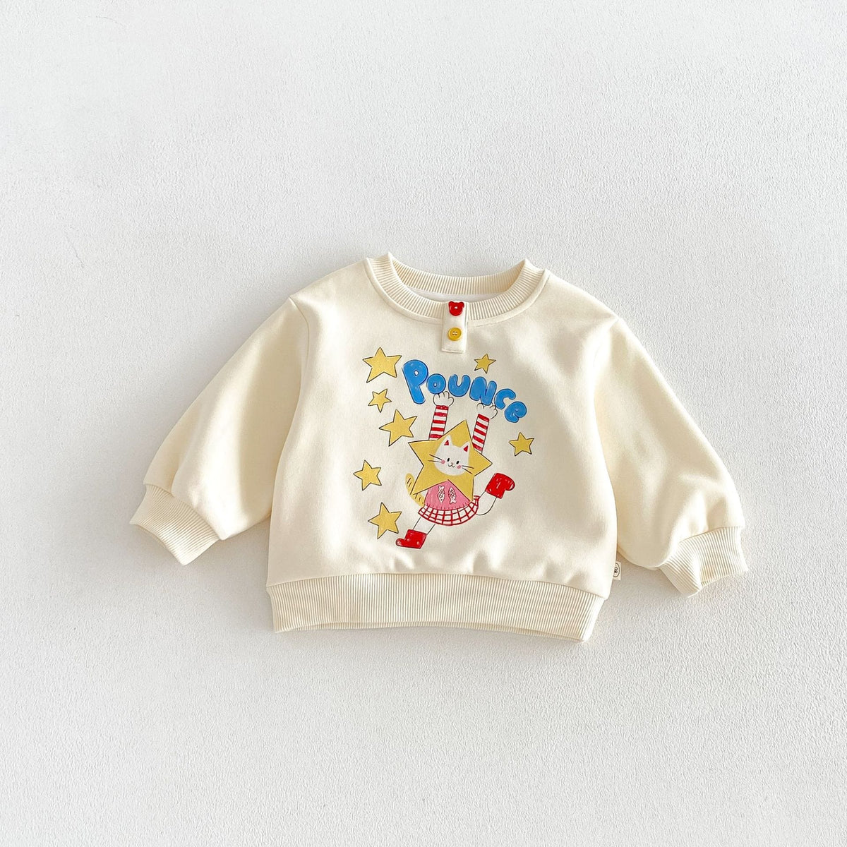クリーム色のキッズ長袖トレーナー、キャラクタープリントとボタン付き首元