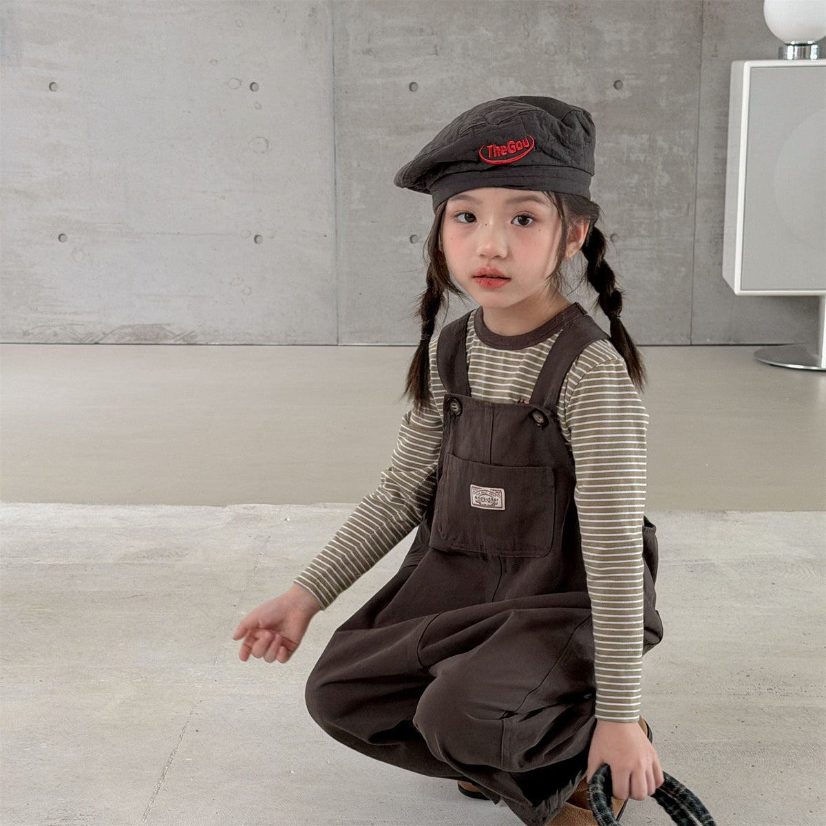 キッズ用ダークブラウンのサロペットパンツ、胸元のワッペン付き