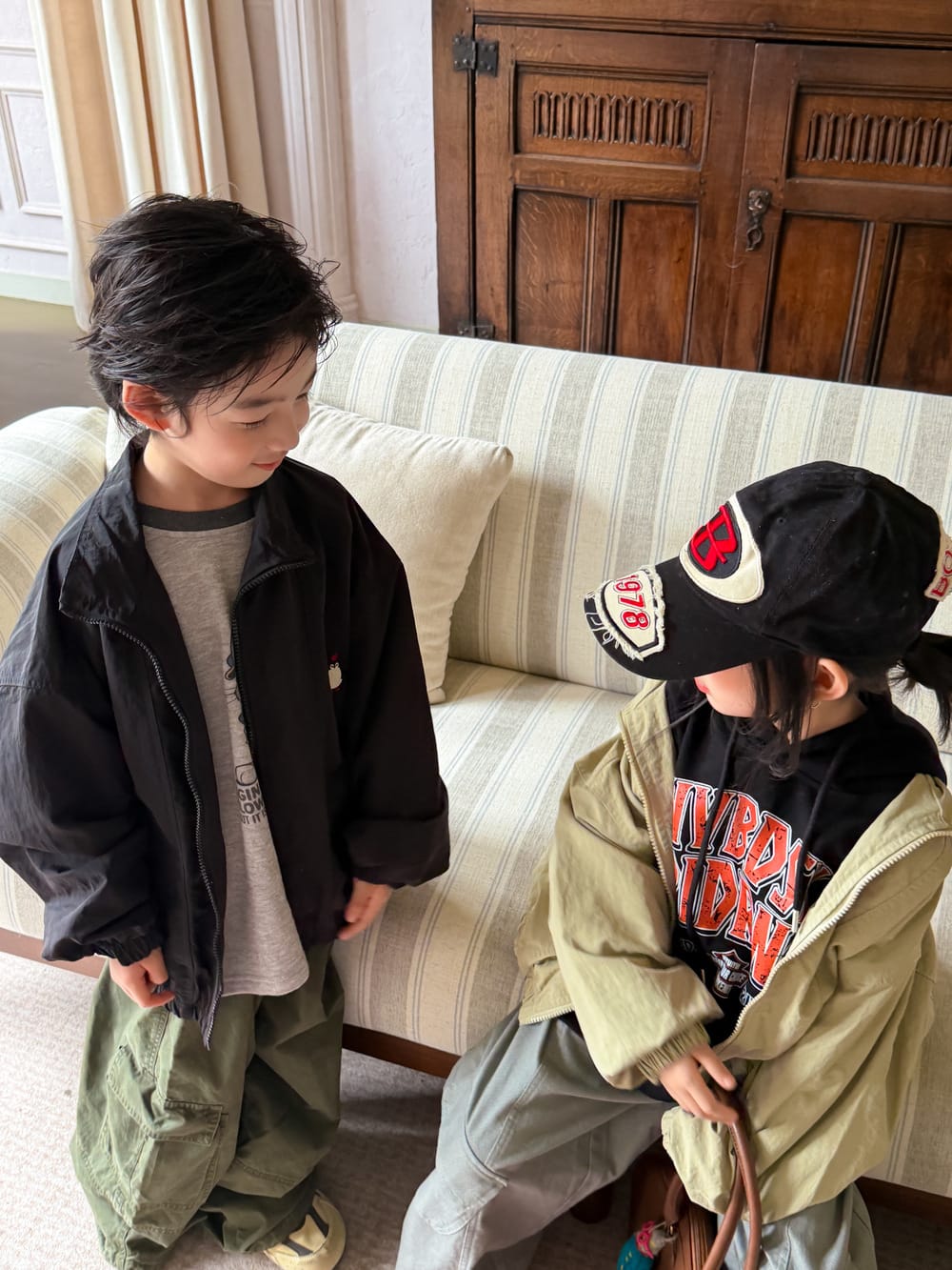 キッズ用黒・カーキのジップアップ襟付きブルゾン、背面ロゴが見える