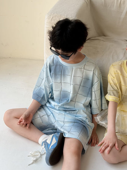 チェック柄の半袖Tシャツ＆ショートパンツセット（青系、座り姿）