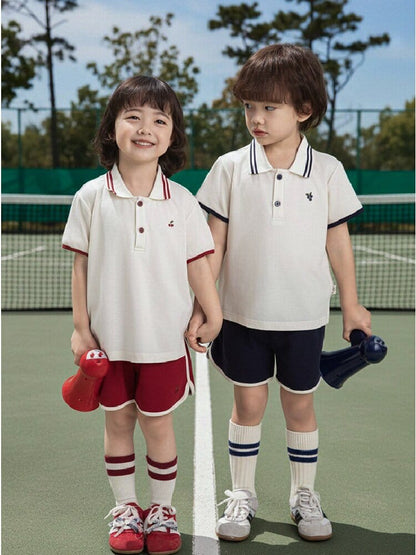 ポロシャツ＆ショートパンツセットアップ：白ポロと赤/紺の短パン、テニスコートで着用
