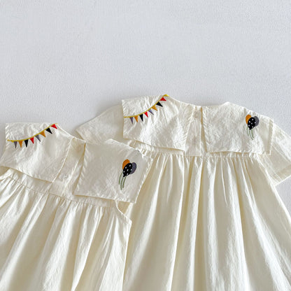 子ども用ホワイトワンピース、胸元の切替フリル。柄はサーカスモチーフ刺繍