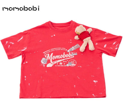 赤い半袖Tシャツ、胸にロゴプリントとくまのぬいぐるみ風アップリケ