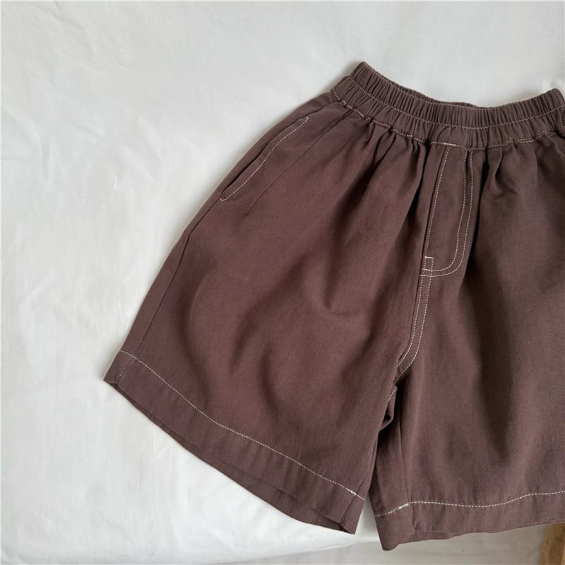 コーヒー色のルーズハーフパンツ、サイドのステッチラインが見える