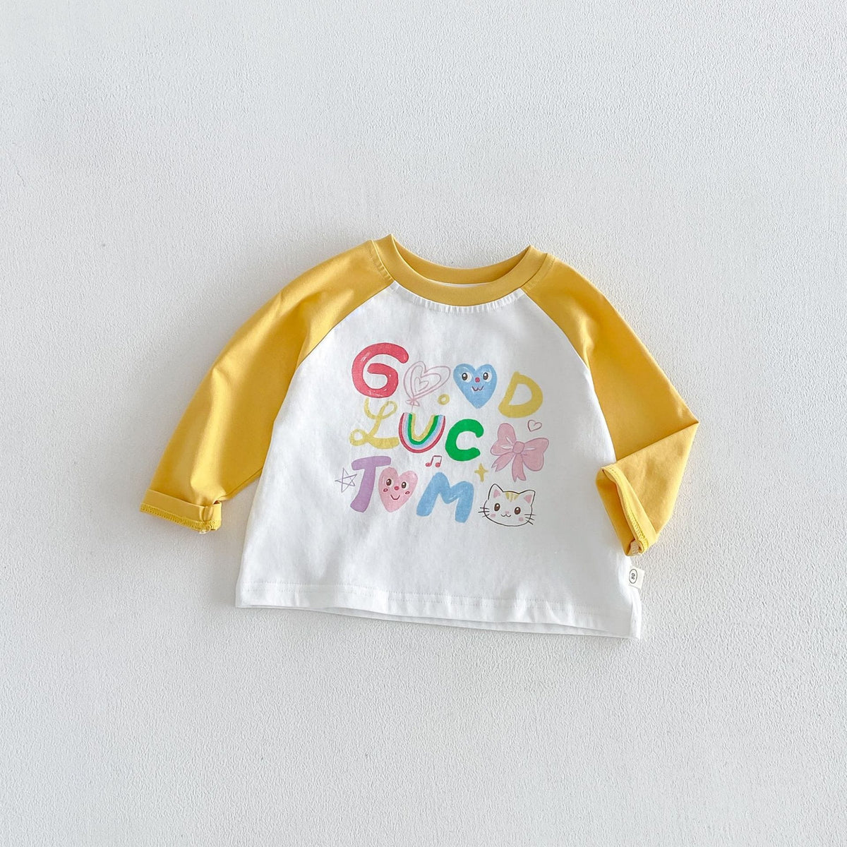 イエロー×白のキッズ用ラグラン長袖Tシャツ 「GUC LUC TUM」キャラプリント
