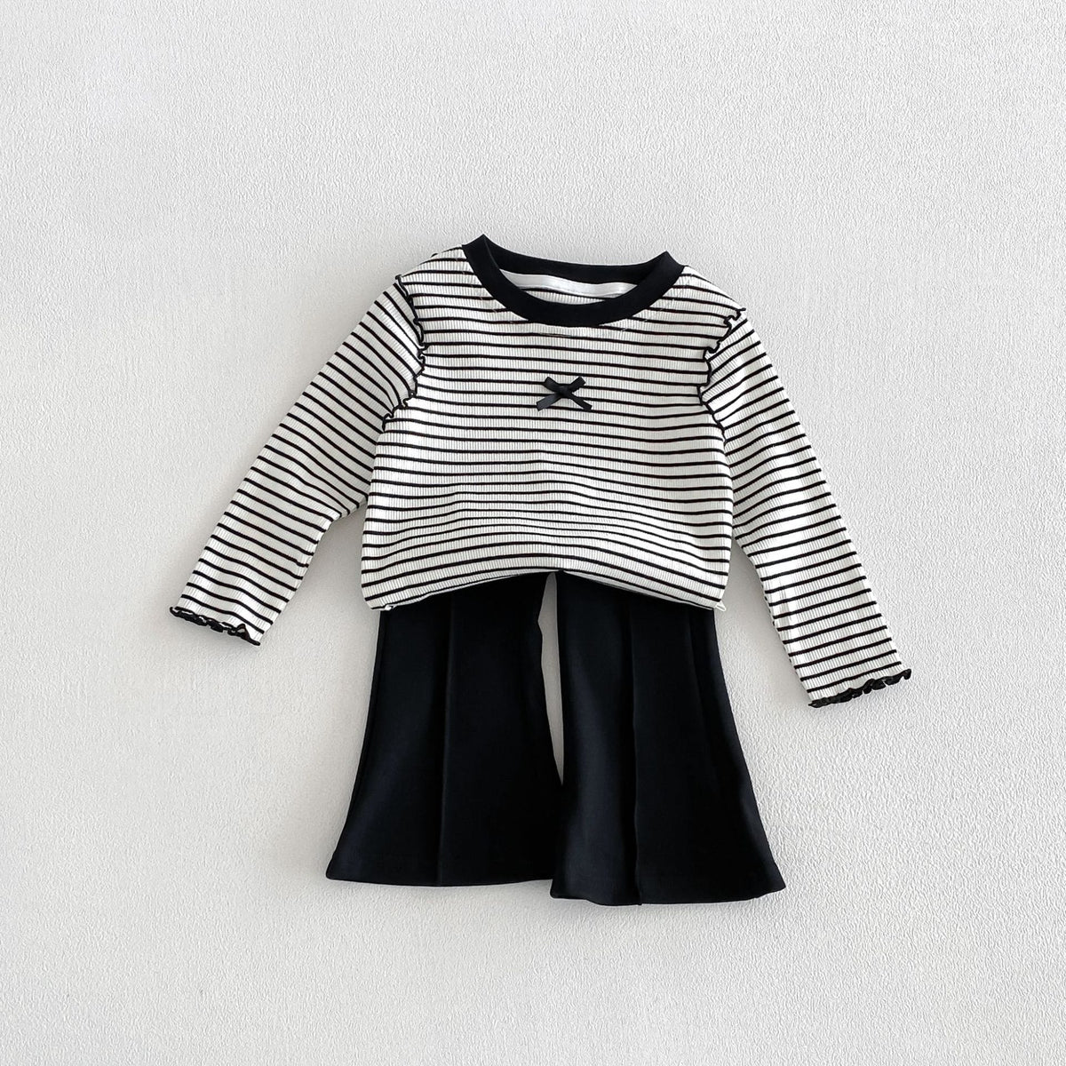 子ども用ボーダー長袖Tシャツ、黒リブ首元とフレアボトム、胸のリボン風モチーフ