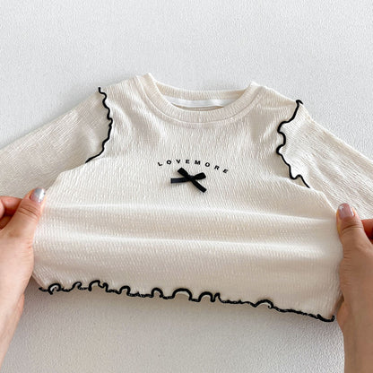 キッズ 白のロゴプリント長袖Tシャツ、メローフリルとリボンステッチ、裾はフリル仕上げ
