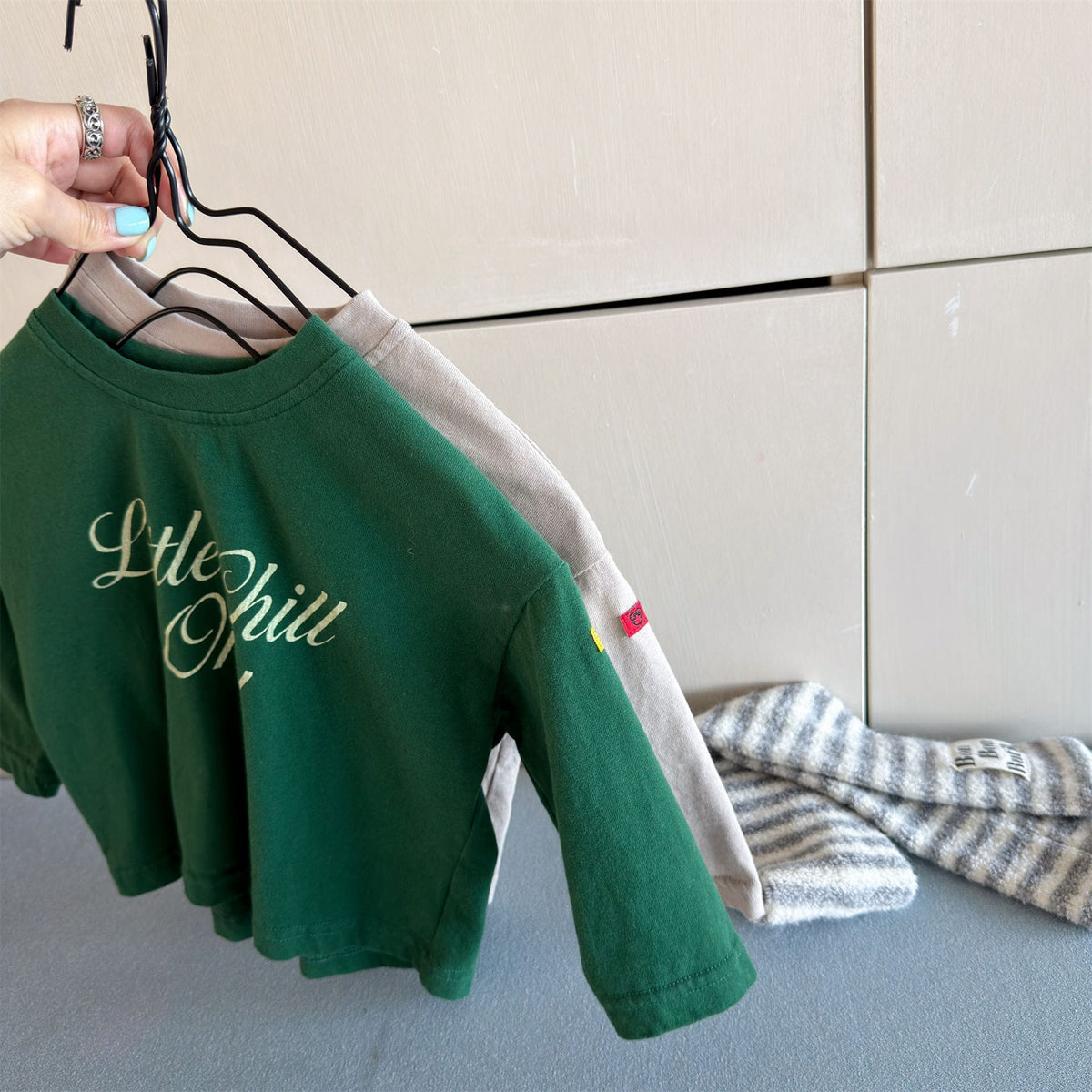 グリーンのキッズ長袖Tシャツ、袖口と英字ロゴプリントの側面