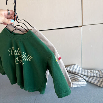 グリーンのキッズ長袖Tシャツ、袖口と英字ロゴプリントの側面