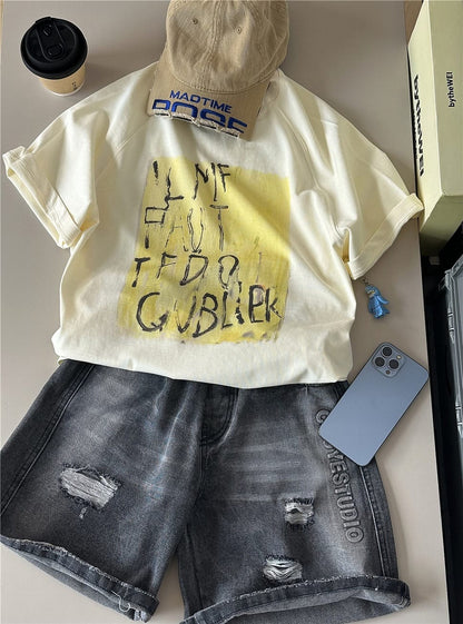 オフホワイト半袖Tシャツ。前面に黄いろの抽象プリントと黒文字風ロゴ。